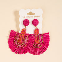Hot Pink Fringe Earrings by The Darling Effect—these boho, fan-shaped earrings with beaded and woven details are displayed on a branded card against a light beige background. Lightweight and perfect for everyday wear.