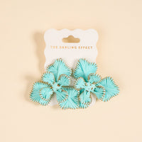 A pair of light blue fan-shaped "Blue Main Character Earrings" by The Darling Effect, with gold edges, perfect for everyday wear, displayed on a white card labeled THE DARLING EFFECT in gold text and set against a beige background.