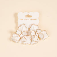 White Main Character Earrings by The Darling Effect: petal-shaped white earrings with gold trim on a light peach background, lightweight for everyday wear, displayed on a card reading THE DARLING EFFECT.