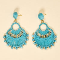 The Darling Effect Teal Paloma Drop Earrings feature a fan shape with gold accents, blue beads, and detailed threadwork. Lightweight and boho-inspired, these earrings are perfect for daily wear and photographed against a neutral backdrop.