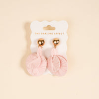 Blush Pretty and Polished Earrings by The Darling Effect feature light pink circular, textured designs on shiny gold studs. Lightweight and ideal for daily wear, they're shown on a branded white card against a beige background.
