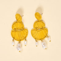 The Darling Effect's Yellow Pearl Affair Earrings feature a yellow, tiered abstract design with three dangling irregular white pearls—lightweight for everyday wear, shown on a light beige background.