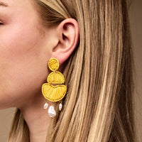 Close-up of a woman's ear wearing The Darling Effect's Yellow Pearl Affair Earrings—lightweight, three-tier yellow boho earrings with dangling pearl-like beads. A standout accessory for everyday wear, beautifully complementing her blonde hair and fair skin.