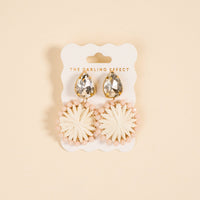 White Radiant Gem Earrings by The Darling Effect feature a raffia sunburst design with pink beads, presented on a branded card—perfect lightweight earrings for everyday wear.