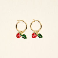 Berrylicious Signature Hoop Earrings by The Darling Effect feature gold hoops adorned with charming red strawberry and green leaf charms, shown against a simple off-white background. These lightweight earrings are ideal for infusing a playful flair into your daily look.
