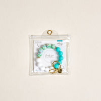 The Darling Effect Cabana Crush Hands-Free Keychain Wristlet features turquoise, white, and floral beads with gold hardware, all in a clear pouch.