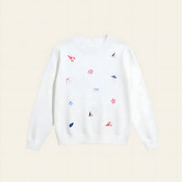 The Darling Effect’s Seaside Haven Refined Knit Sweater is a white crewneck adorned with red embroidered lobsters, blue sailboats and bows, and pink seashells—a charming staple for any wardrobe.