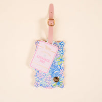 The Darling Effect’s Coastal Cove Jetsetter Luggage Tag features a floral print in pink, blue, and green on a beige background, with a pink strap, gold buckle, privacy flap, and “Jetsetter Luggage Tag” text.