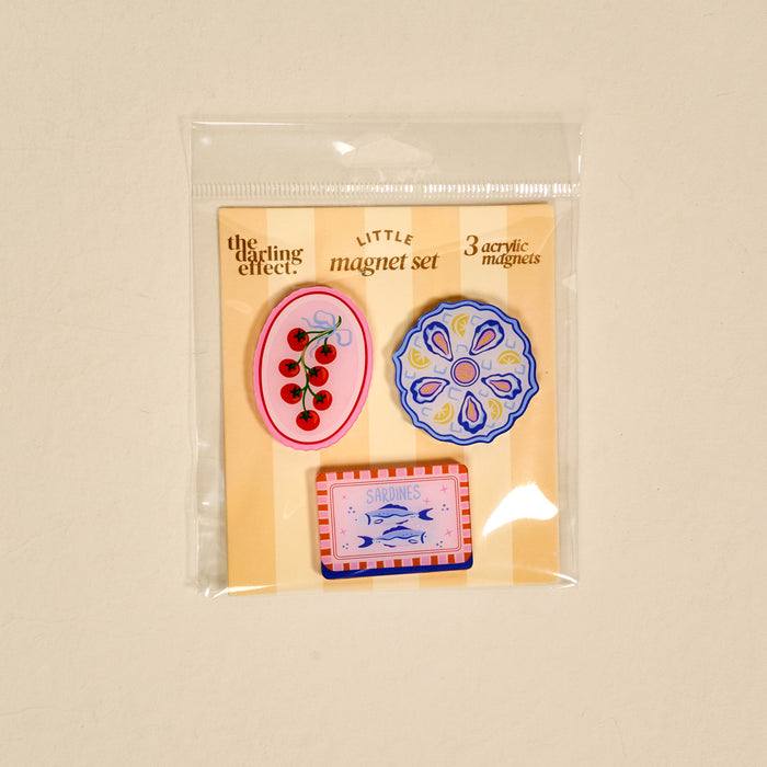 The Capri Catch Little Magnet Set by The Darling Effect includes three delightful fridge magnets—cherries on pink, a blue and white flower, and a sardines tin—making them perfect decorative accents for any magnetic surface.