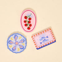 The Darling Effect's Capri Catch Little Magnet Set features three illustrated coasters—tomatoes, oysters and lemons, and sardines—that make perfect decorative accents or pair beautifully with the matching acrylic magnets for your kitchen decor.