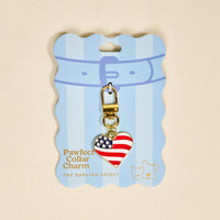The Darling Effect Americana Heart Pawfect Collar Charm features a heart-shaped American flag design, gold clasp, and blue packaging with two pet illustrations—a patriotic accessory for your pet.
