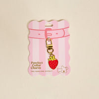The Darling Effect’s Strawberry Pawfect Collar Charm features a gold clasp and comes on pink and white striped packaging, making it the perfect cute accessory for your pet’s collar charm collection.