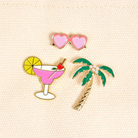Vacation Mode The Pin Pack by The Darling Effect includes three collectible pins: pink heart-shaped sunglasses, a pink margarita with lemon slice and cherry, and a palm tree adorned with pearl accents.