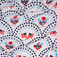 The Darling Effect's All-American Darling Snuggle Up Plush Blanket features white fleece with American flags, florals, stars, hearts, and medallion borders—a cozy throw for timeless patriotic style.