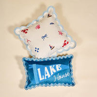 The Darling Effect’s Lake House Scalloped Rectangle Throw Pillow pairs a “LAKE House” text design with blue flag and scalloped trim, creating a charming accent for your space.