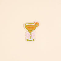 The Darling Effect Bow-Tied Margarita Mix & Match Iron-On Patch features a cocktail glass with an orange slice and pink bow—perfect for adding a pop of color and customizing your look.