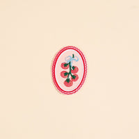 The Darling Effect’s Off the Vine Mix & Match Iron-On Patch features bright red tomatoes tied with a blue bow on a pale pink background with scalloped borders—perfect for customizing your items with a touch of color.