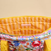 A close-up of The Darling Effect's Ciao Bella The Everyday Quilted Tote Bag, featuring a colorful seafood pattern, yellow zipper, striped interior with zip pocket, and a pink label—perfect for everyday use.