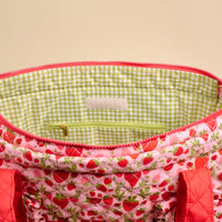 Discover the Strawberry Fields The Everyday Quilted Tote Bag by The Darling Effect—an open, quilted tote featuring a charming strawberry pattern and vibrant red handles. The spacious interior is lined with green and white gingham check fabric and includes a convenient zippered pocket. Shown open to reveal the pocket and inner design, this bag is perfect for carrying all your daily essentials in style.