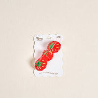 The Darling Effect’s Tomatoes Shape Up Claw Clip is attached to a white, wavy-edged card reading “the styling effect. 1 shape claw clip. Hold your hair back in style.” Perfect for giving your hairstyle a cute tomato-inspired touch.