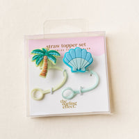 The Island Escape Straw Topper Set by the-darling-effect features two leak-resistant silicone toppers—one palm tree, one blue seashell—ideal drinkware accessories, shown on a white background with branded “straw topper set” packaging.
