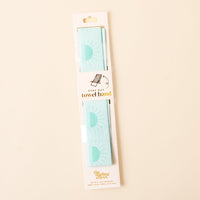 The-darling-effect’s Put Towel Band-Sunshine Aqua Stay is a mint green no-slip towel band with a sun pattern, packaged on a white card featuring gold "Stay Put Towel Band" text.