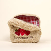 The Darling Effect’s Square Farm Fresh Strawberries Teddy Pouch features fluffy beige sherpa with embroidered strawberries and "Strawberries" below, plus a red and white gingham lining—a charming accessory for any collection.