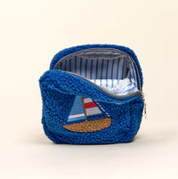 The Darling Effect’s Square Sail Boat Teddy Pouch is a small blue sherpa zip pouch with blue-and-white striped lining and an embroidered sailboat—a charming accessory or addition to any teddy pouch set.