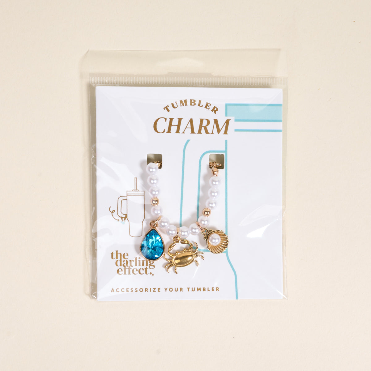 Add coastal flair to your tumbler with The Darling Effect’s Seaside Sparkle Tumbler Charm, featuring a blue gem, gold crab, and gold seashell—an eye-catching accessory for your handle.