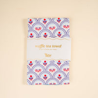 A folded All-American Darling Waffle Tea Towel by The Darling Effect, featuring a red, blue, and purple floral pattern, wrapped in a labeled band—an absorbent kitchen towel that doubles as a decorative tea towel.