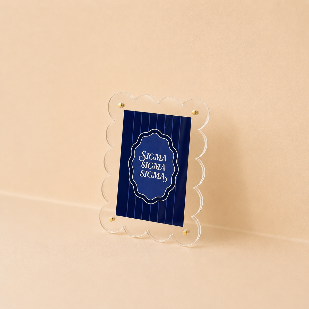 The Darling Effect's Sigma Sigma Sigma Mini Acrylic Picture Frame Magnet features a blue card with “SIGMA SIGMA SIGMA” in white, displayed in a clear, scalloped-edged frame with gold screws—ideal for fans of unique mini frames.