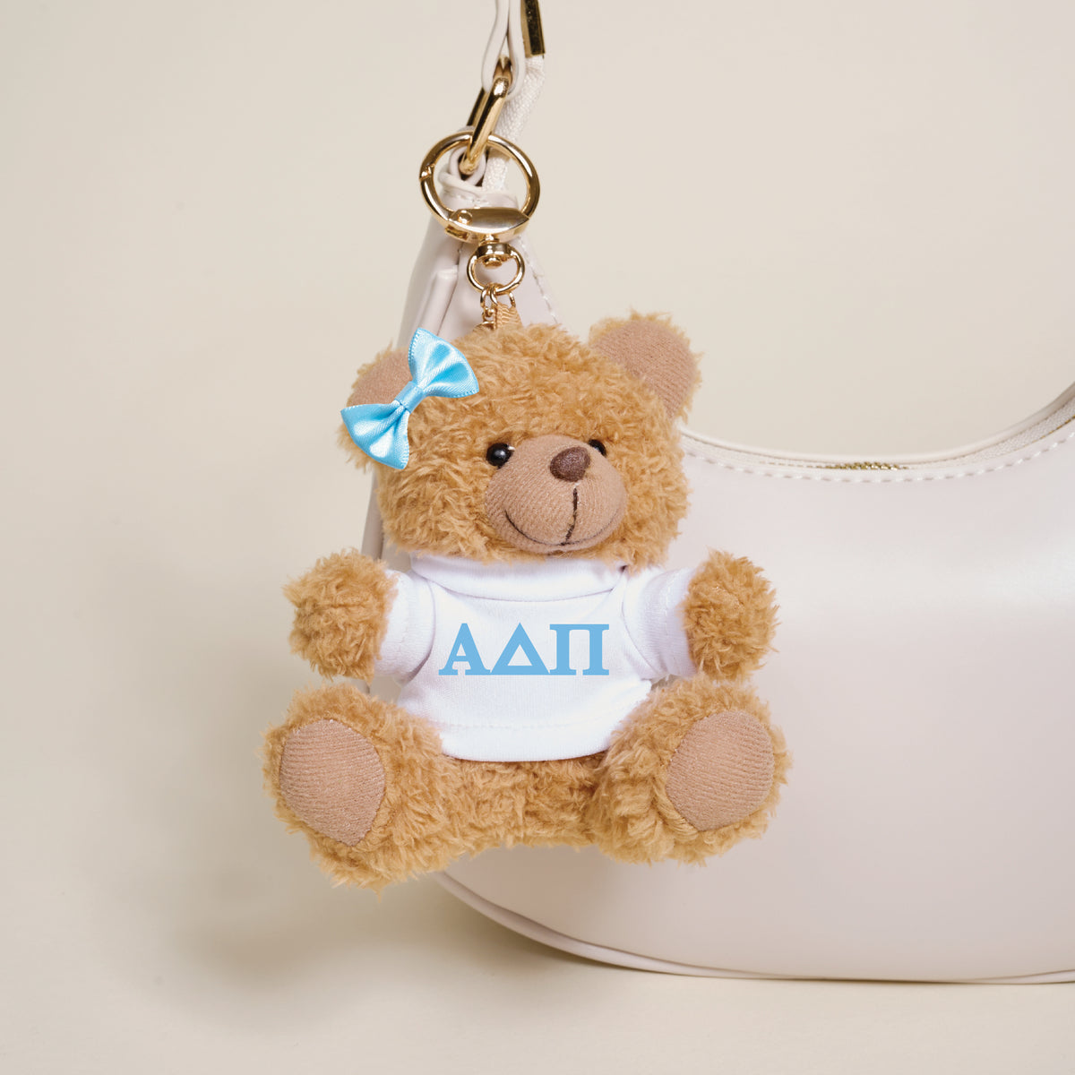 The Darling Effect’s Alpha Delta Pi Teddy Bear Bag Charm features a small brown bear with a blue bow and white shirt with blue Greek letters—an adorable accessory for your bag or the perfect Bid Day gift.