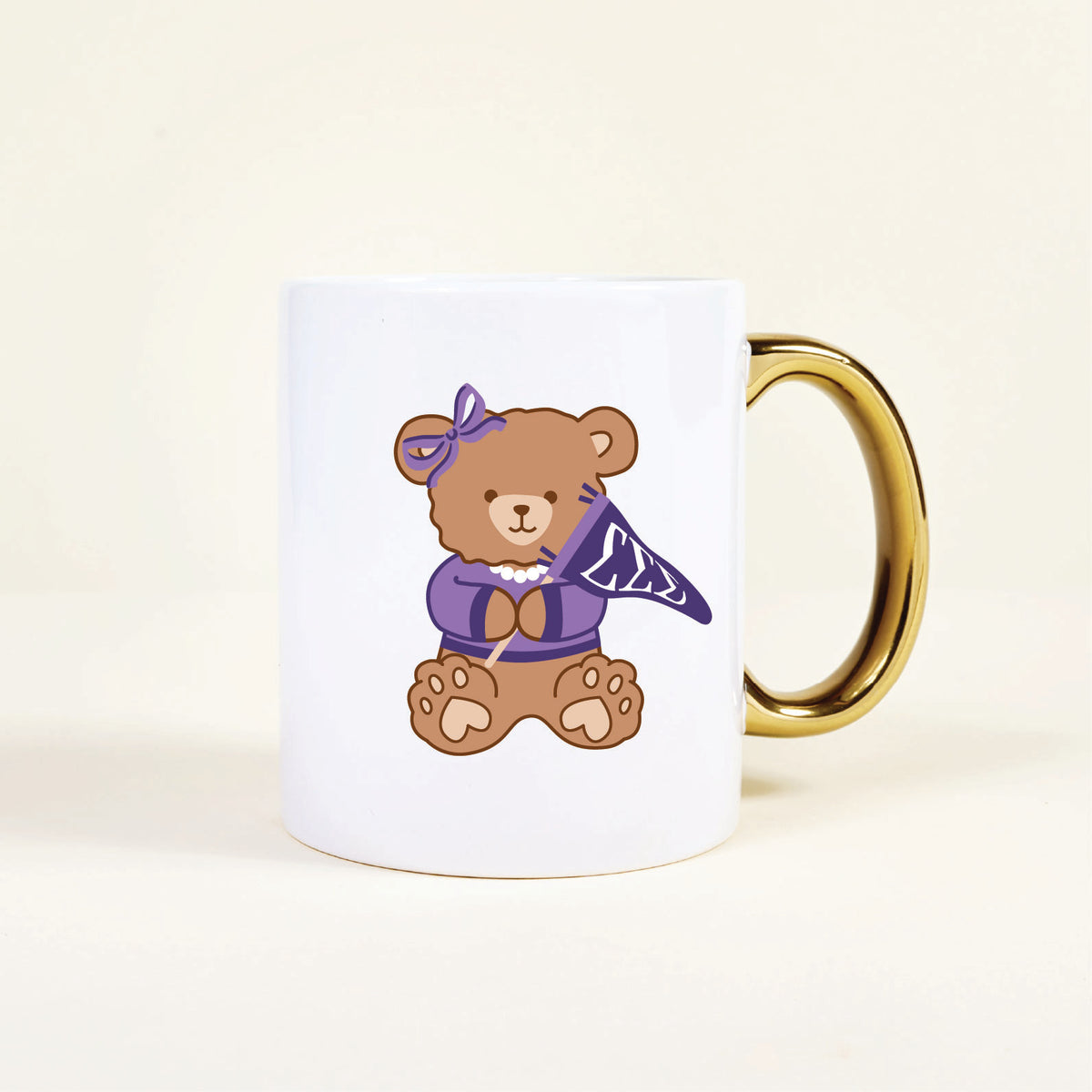 The Darling Effect’s Sigma Sigma Sigma 11 oz Cozy Cute Ceramic Mug features a ceramic teddy bear with a gold handle, purple bow, pearl necklace, and patterned scarf—perfect for any sorority mug collection.
