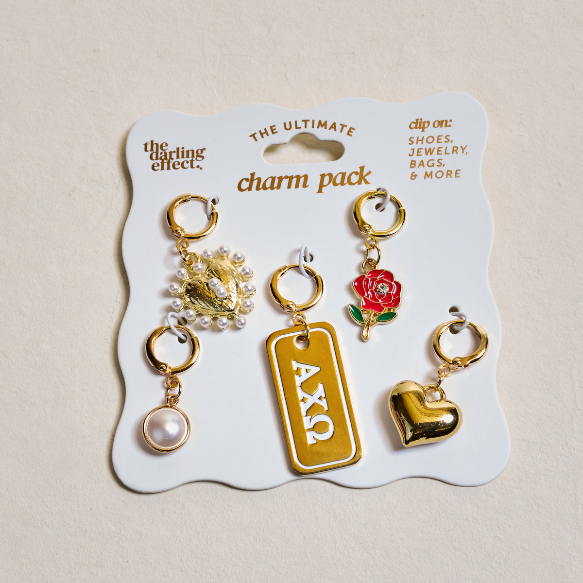 Show off your sorority spirit with The Darling Effect's Alpha Chi Omega The Ultimate Charm Pack—five gold charms on a display card, featuring a pearl, two hearts, a red rose, and an ΑΧΩ tag.