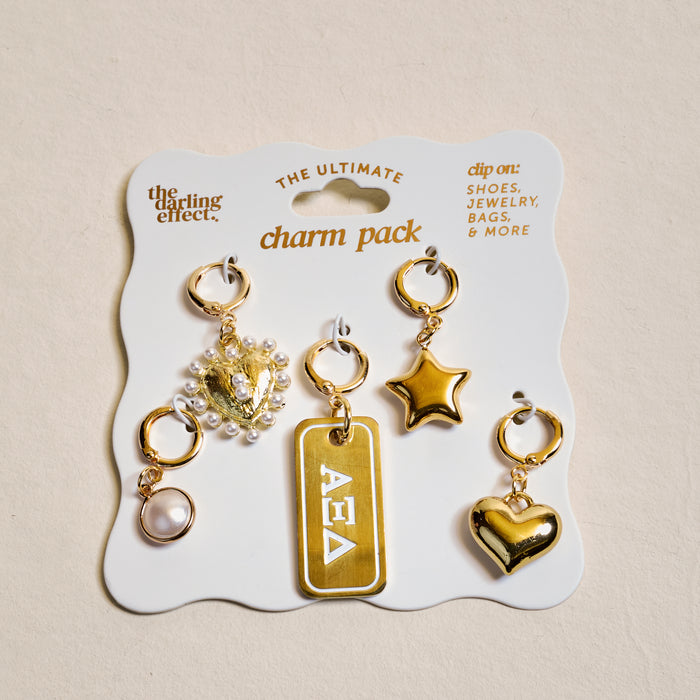 The Darling Effect’s Alpha Xi Delta The Ultimate Charm Pack features five gold clip-on charms—a pearl, lion head with pearls, Greek letters, star, and heart—displayed on a card to show your sorority spirit on necklaces.