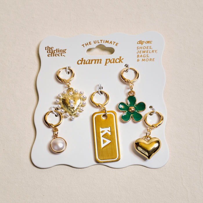 The Darling Effect’s Kappa Delta The Ultimate Charm Pack includes five gold-tone charms—a heart, green flower, pearl, pearl-embellished gold charm, and a gold rectangle with Greek letters—perfect for sorority-inspired necklaces.