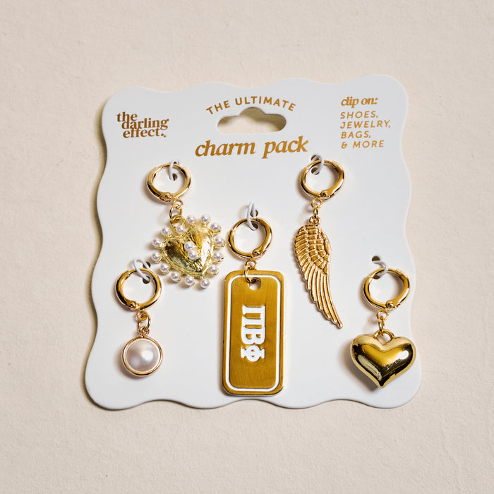 The Darling Effect’s Pi Beta Phi The Ultimate Charm Pack features five gold charms—a pearl, lion head with pearls, “IDB” tag, wing, and shiny heart—perfect for customizing shoes, bags, or creating unique sorority jewelry.