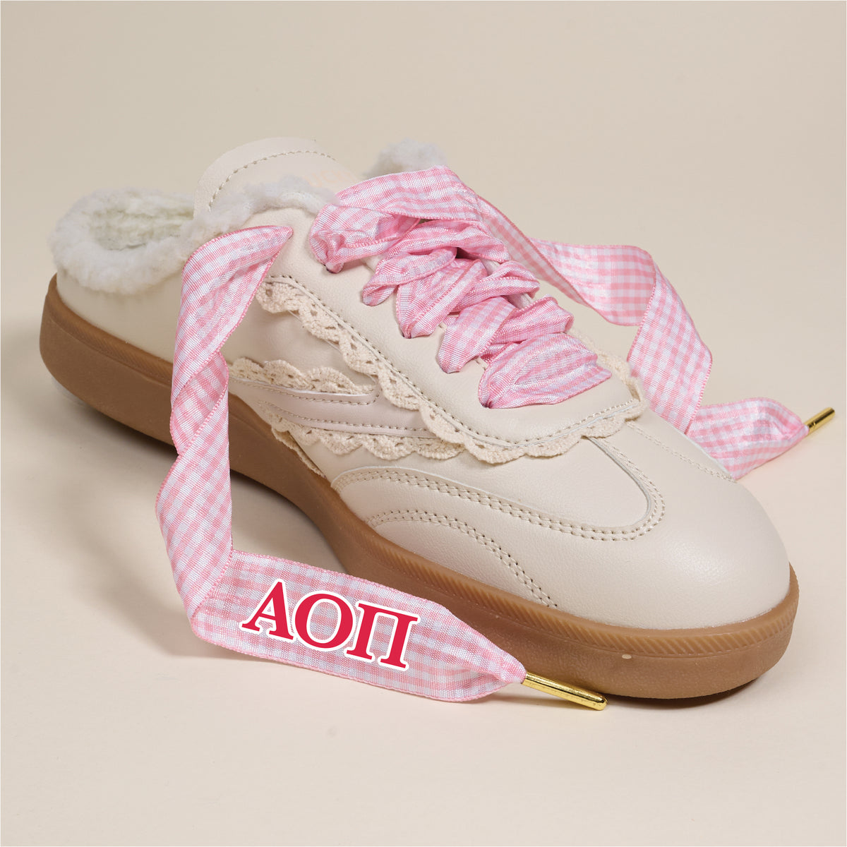 The Darling Effect's Alpha Omicron Pi Step It Up Shoelaces feature pink gingham laces with red ΑΟΠ embroidery—perfect cute sorority gifts. Cream slip-on style, brown sole, lace trim, and soft sherpa lining inside.