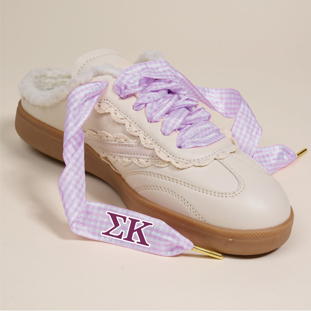 The Darling Effect's Sigma Kappa Step It Up Shoelaces feature light purple gingham with gold tips and the ΣΚ symbol, shown here on a cream sneaker with fluffy interior and beige lace trim—ideal for sorority gifts against a neutral backdrop.