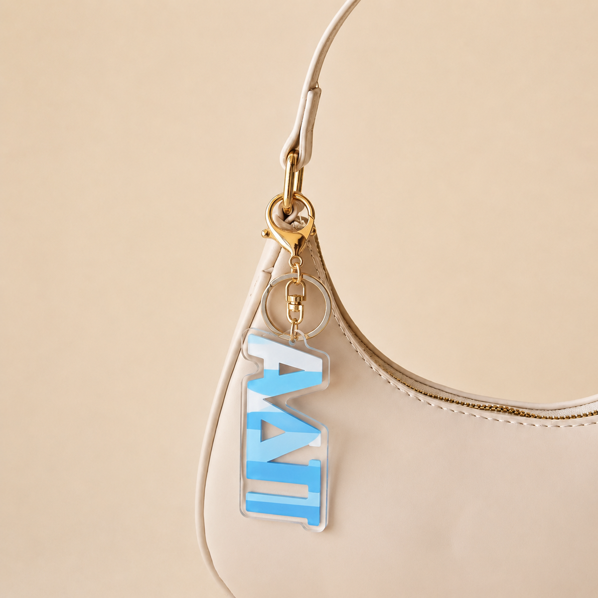 A cream-colored handbag with a gold zipper and The Darling Effect’s Alpha Delta Pi Stripes Acrylic Keychain—featuring a blue and white tag—makes a perfect, stylish sorority gift for statement-makers.