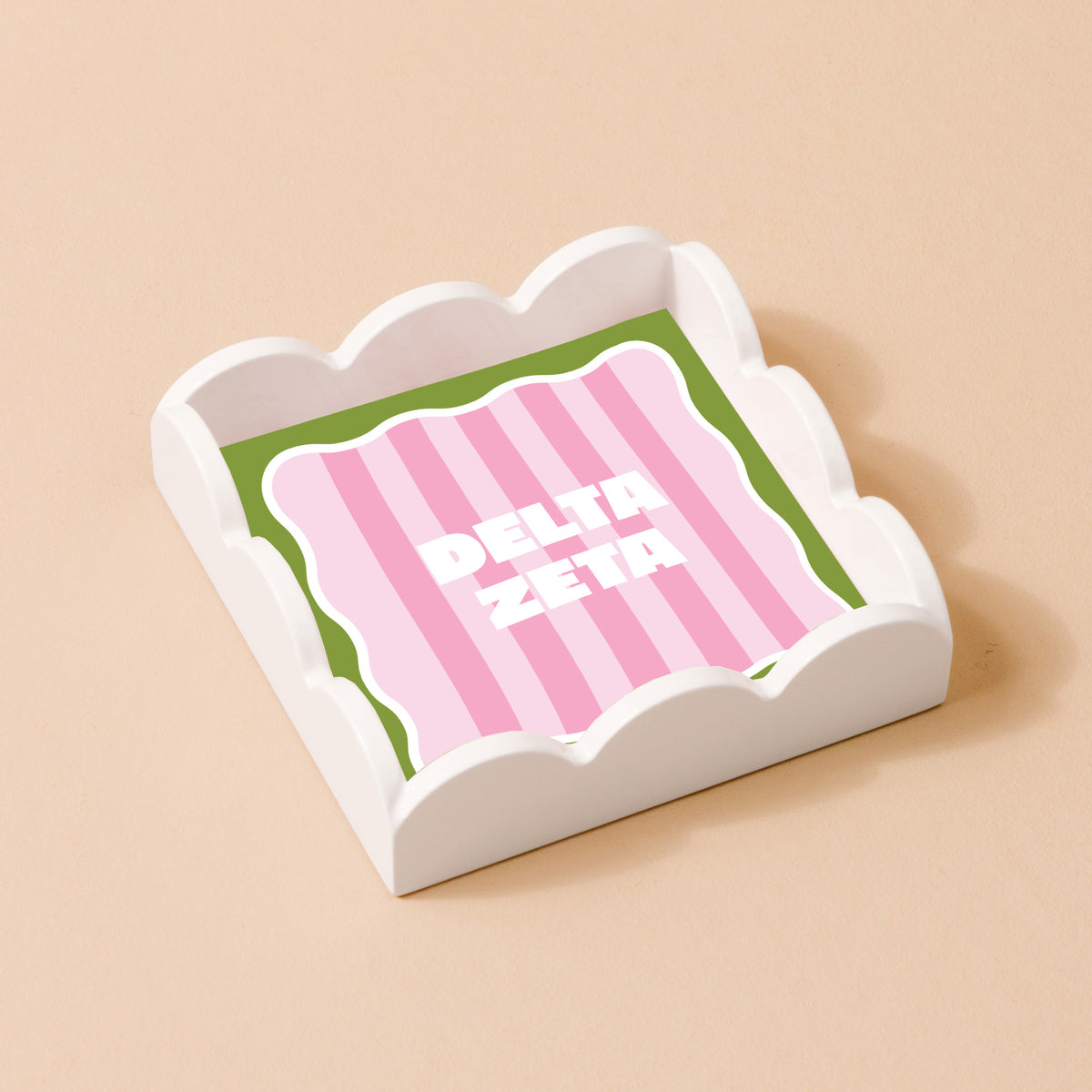 The Darling Effect's Delta Zeta Scallop Trinket Tray features a pink and green striped insert with bold white "DELTA ZETA" lettering, ideal as a vanity tray or jewelry organizer.