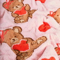 Snuggle up with The Darling Effect's Teddy Bear Hugs Cozy Dreams Luxe Blanket, a pink ultra-soft microfiber throw featuring brown teddy bears with red hearts and bows—perfect for warm, cozy nights in!.