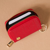 The Red Hearts Zip Around Wallet by The Darling Effect is a red, heart-quilted zip-around keyring wallet featuring a gold ring and an internal card slot containing a white card.