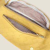 A close-up of The Darling Effect’s Woven Mustard Trendy Luxe Belt Bag reveals a zippered pocket, beige and white striped lining, and a gold zipper pull, blending hands-free style with chic woven design.