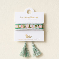 A woven bracelet with green and pink embroidered “Pickleball Yall” on a white and mint band, displayed on a card reading “The Darling Effect” with matching mint and white tassels below. Adjustable for a perfect fit.