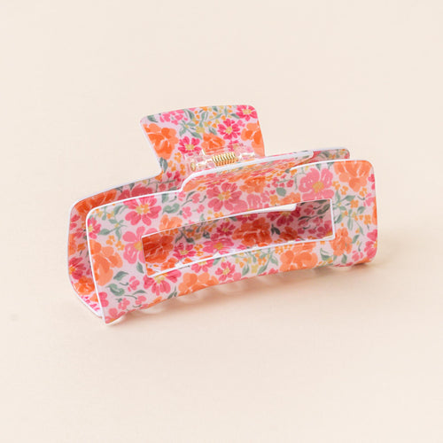 The-darling-effect's Secret Garden Pink Claw Clip features pink and orange floral print on a light pink background, adding vibrant color and a secure hold to any hairstyle.