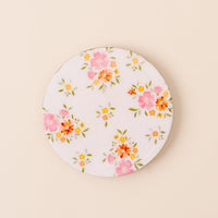 The-darling-effect’s Endless Daydream Cream Wood Enamel Coaster features a white base with pink, orange, and yellow floral designs—perfect for brightening your space. Shown on a light beige surface.