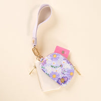 The Bouquet Beauty Purple Dynamic Duo Pouch Wristlet by the-darling-effect features a small floral-patterned coin purse with a lavender strap and gold hardware, holding a pink card and attached to a clear pouch, on a light cream background.
