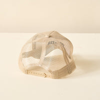 The Darling Effect Boy Mom Trucker Hat is shown from the back, featuring a beige mesh design with an adjustable snapback closure, classic trucker style, and displayed on a light surface against an off-white background.