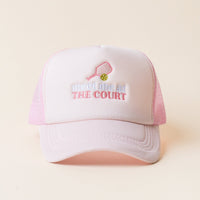 The Meet Me at the Court Trucker Hat by the-darling-effect features pink and white panels, mesh sides, an embroidered pink pickleball paddle with a green ball, and "meet me at THE COURT" on the front.